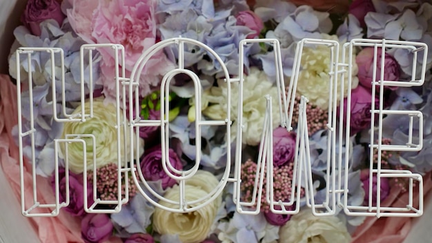 Photo floral flowers background with the inscription home with water droplets wooden letters closeup top