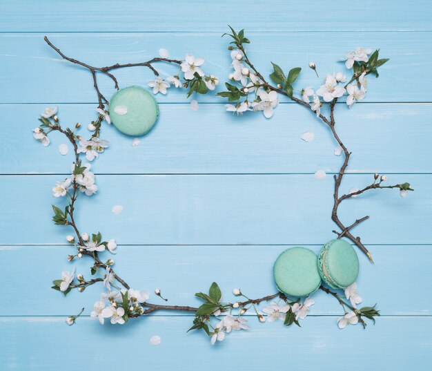 Floral frame and dessert macaroons on a blue wooden background