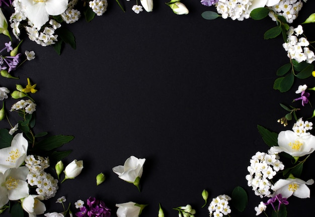 Floral frame gemaakt van verschillende lentebloemen op zwarte achtergrond bloemen plat leggen ruimte voor tekst