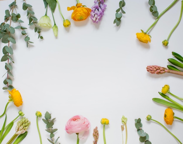 Floral frame of pink and orange ranunculus hyacinth and eucalyptus on a white background top view