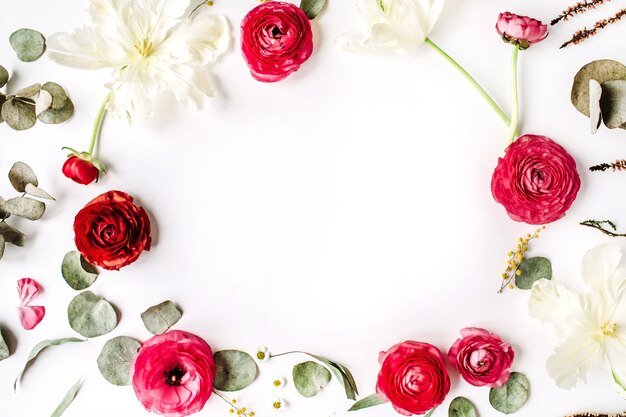 Floral frame of pink and red roses or ranunculus, white tulips and green leaves