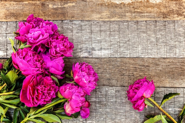 古いぼろぼろの素朴な木製の背景のコピースペースに新鮮な咲くピンクのマゼンタの牡丹の花の花束と花柄フレーム庭のエコカラフルな自然生態学の概念の春または夏