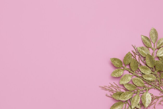 Floral golden glitter branches on pink table with copy space