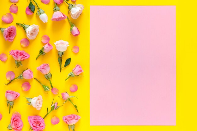 ピンクとベージュのバラで作られた花柄、黄色の背景に緑の葉。バレンタインデーの背景。