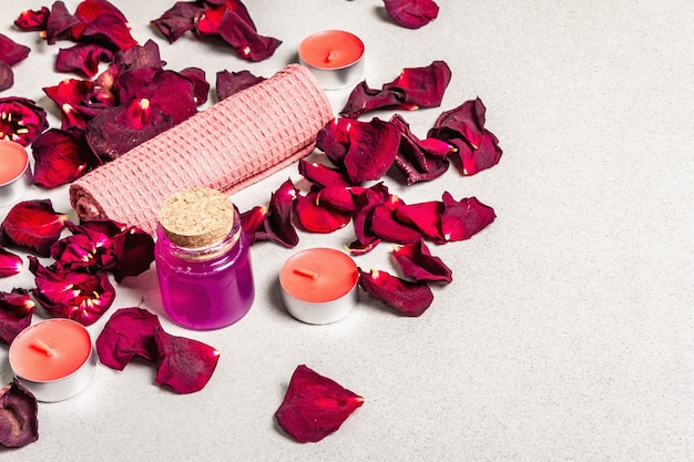Цветочная и спа-концепция с засушенными лепестками роз, ароматными свечами и мягким полотенцем