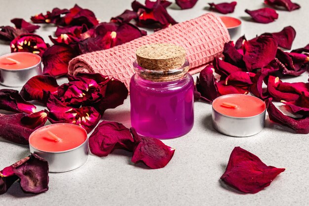 Photo floral and spa concept with dried roses petals, fragrant candles and soft towel