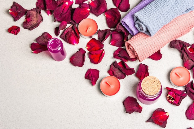 Floral and spa concept with dried roses petals, fragrant candles and soft towel