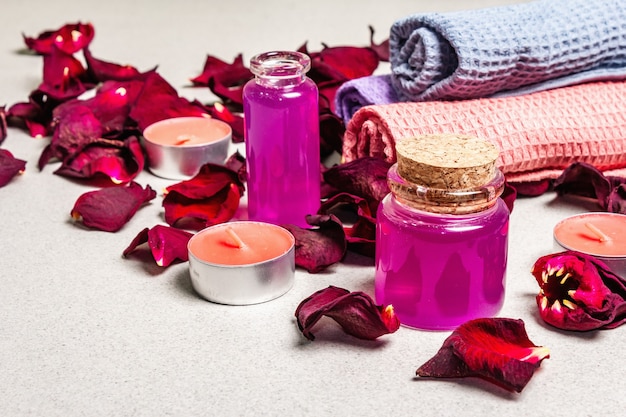 Цветочная и спа-концепция с засушенными лепестками роз, ароматными свечами и мягким полотенцем
