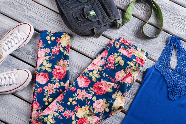 Floral trousers and blue top denim bag and canvas shoes womans clothing on gray shelf sense of style