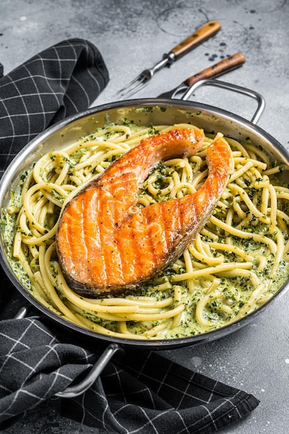 Florentijnse pasta met romige spinaziesaus en gegrilde zalmsteak. Grijze achtergrond. Bovenaanzicht.