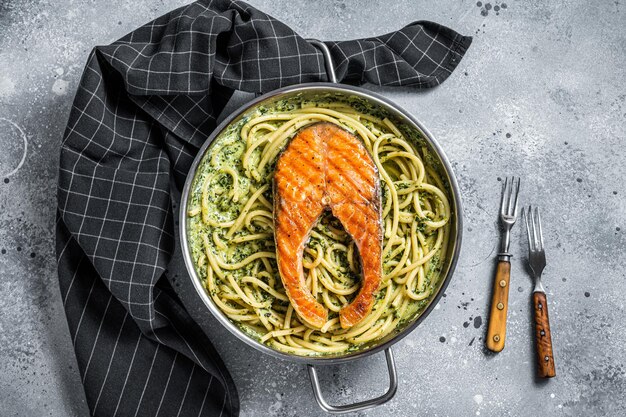 Florentijnse pasta met romige spinaziesaus en gegrilde zalmsteak. Grijze achtergrond. Bovenaanzicht.