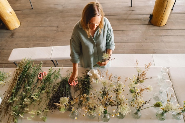 Florist arranging various green plants on a table in a brickwalled workshop