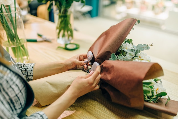 Florist attaches a bow to fresh flower composition