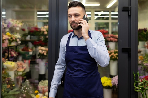 florist businessman talking on the phone next to the refrigerator with flowers.