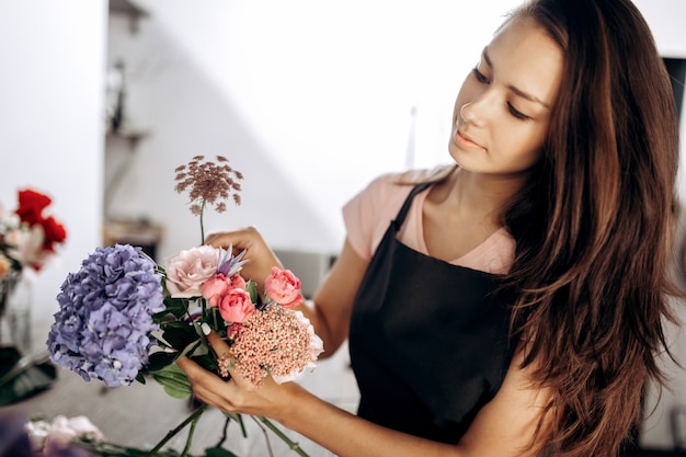 Florist collections a bouquet of fresh pink little roses, blue hydrangea and other flowers in the flower shop .