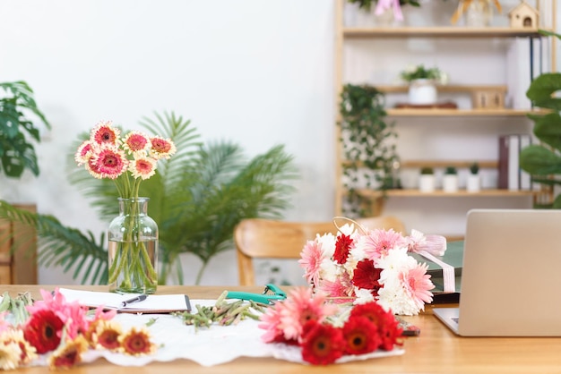 写真 花屋のコンセプト カラフルなガーベラの花瓶とフラワー ショップでの機器と紙袋の花