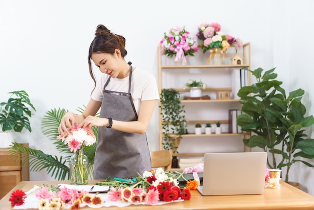 플로리스트 개념 꽃집에서 꽃병에 분홍색 거베라와 국화를 배열하는 여성 플로리스트
