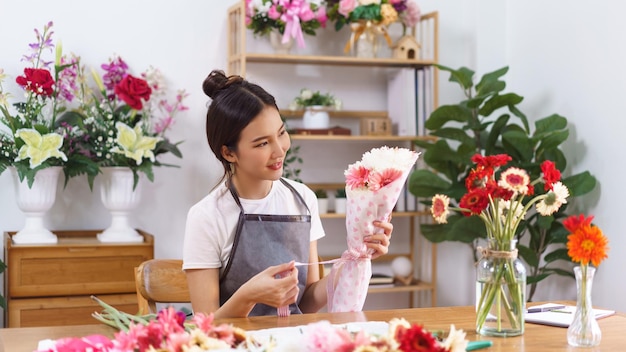 花屋のコンセプト女性の花屋の笑顔と紙とリボンの弓でカラフルな花束を保持