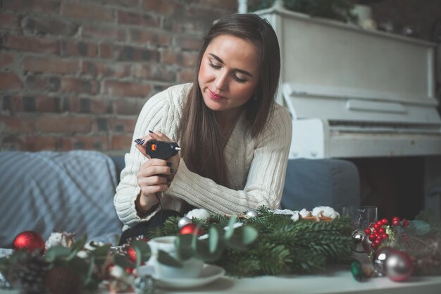 電気ホットグルーガンとクリスマスの装飾を持つ花屋またはデコレータの女性