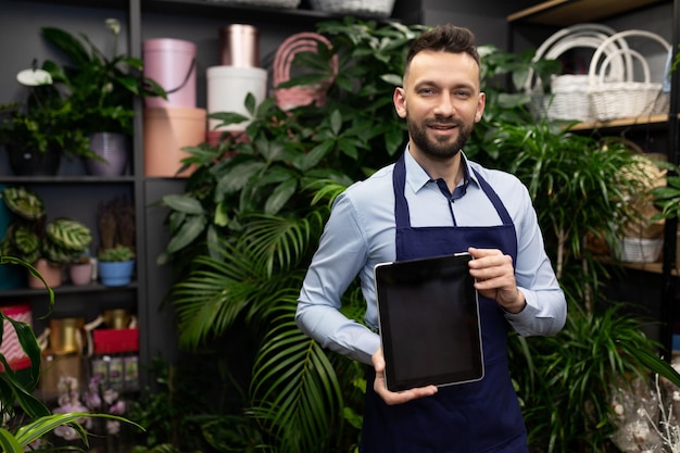 Florist demonstrates tablet screen in bouquets and potted plants shop