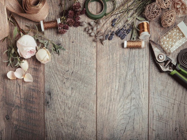 Florist equipment with flowers on wooden background top view