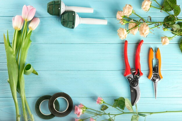 Florist equipment with flowers on wooden background