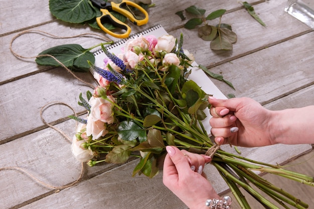 Florist makes a bouquet of rose flowers. The decorator works in a greenhouse with a pink bouquet. Floristic workshop, skill, decor, small business concept