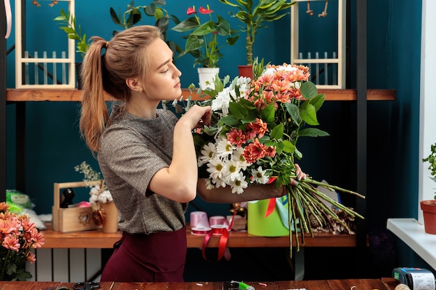 花屋は花束を作ります。若い大人の女の子は、彼女の手に色とりどりの菊の大きな花束を持って、それをチェックします。