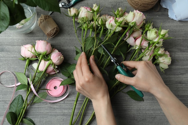 Florist making roses bouquet on dark textured