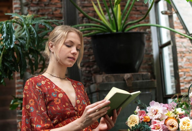 Флорист читает книгу в цветочном магазине