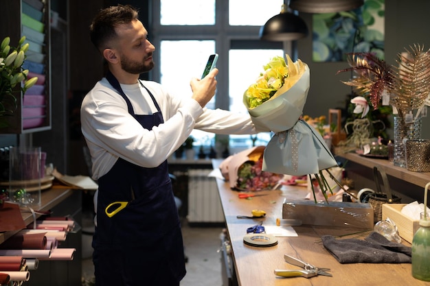 Photo the florist shoots a fresh bouquet on the phone at the workplace