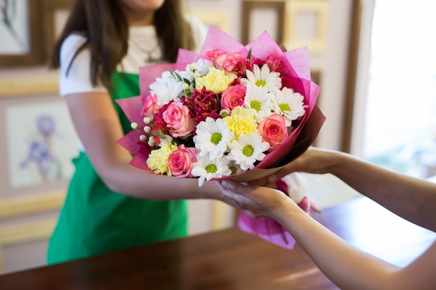 Foto il fiorista darà al cliente un bellissimo bouquet di fiori