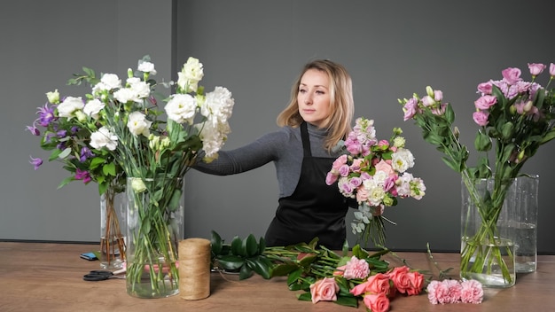 Florist woman composes elegant bouquet with colorful flowers