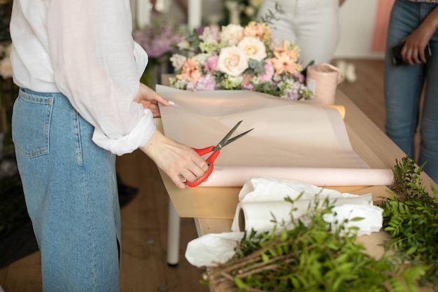 植物とテーブルに紙を切る花屋の女性