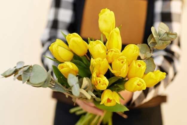 新鮮な黄色のチューリップの美しい花束を保持している花屋の女性。花の配達