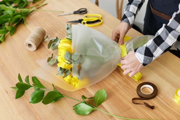 花屋の女性は新鮮な黄色いチューリップの花束を作ります。花柄スタジオ