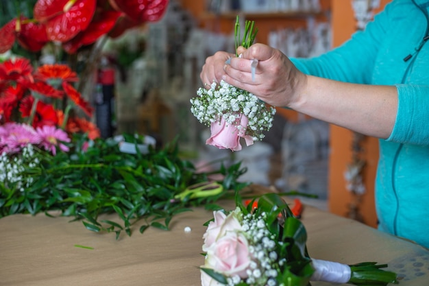 Florist woman ties a bouquet with roses  in a flower shop