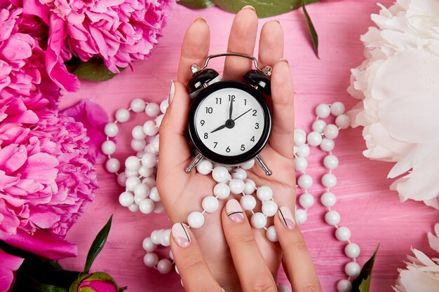 Florist at work, Hands of woman hold alarm clock.