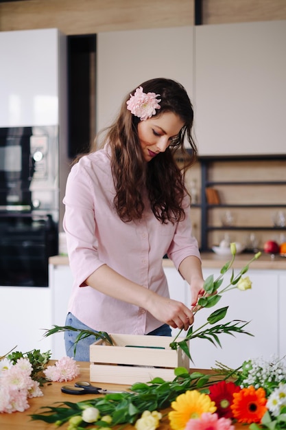 Florist at work pretty young brunette woman making fashion modern composition of different flowers at home