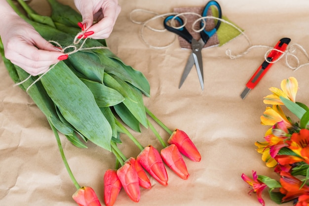 florist at work. woman hands making a tulip bouquet
