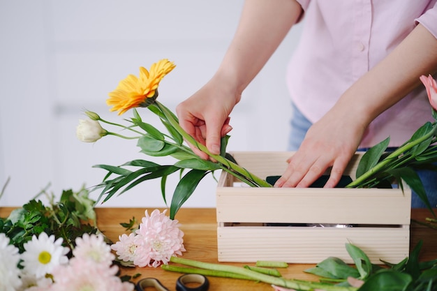 仕事で花屋若いブルネットの女性の手は、自宅でさまざまな花のファッションモダンな構成を作る