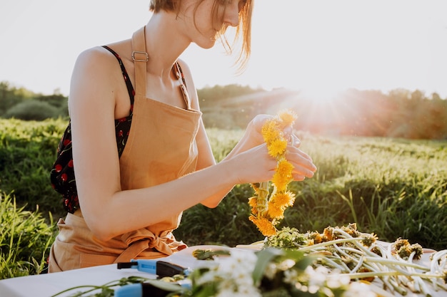 花屋のワークショップ。タンポポから花輪を作るきれいな女性。仕事で花屋のロマンチックな背景。