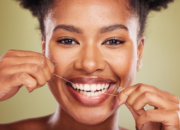 Floss tanden en portret van een zwarte vrouw met tandheelkundige tandarts en mond wellness promotie in groene studio Jong Afrikaans model tandreinigingsproduct en tandzijde voor reclame voor de gezondheidszorg