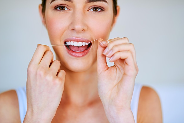 Floss that teeth Cropped shot of a beautiful young woman flossing her teeth