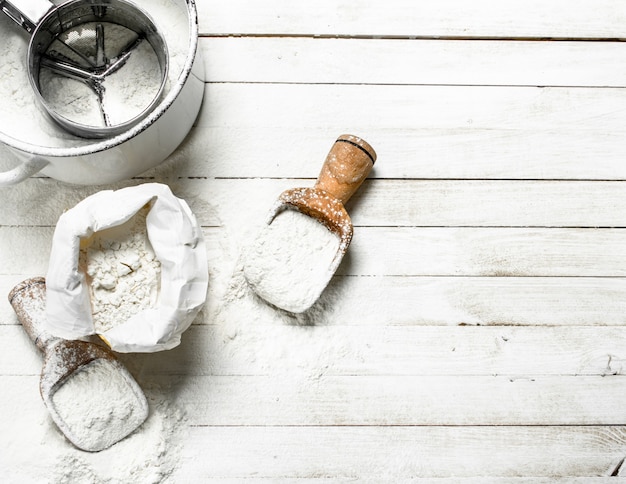 Flour in bag with a shovel on a white wooden table