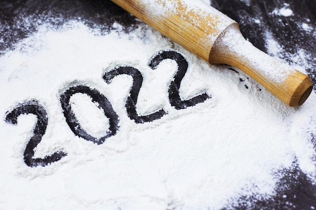 Flour on a black background in the form of numbers 2022 New year and Christmas cooking at home