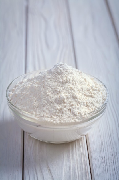 Flour in bowl on old painted wooden board