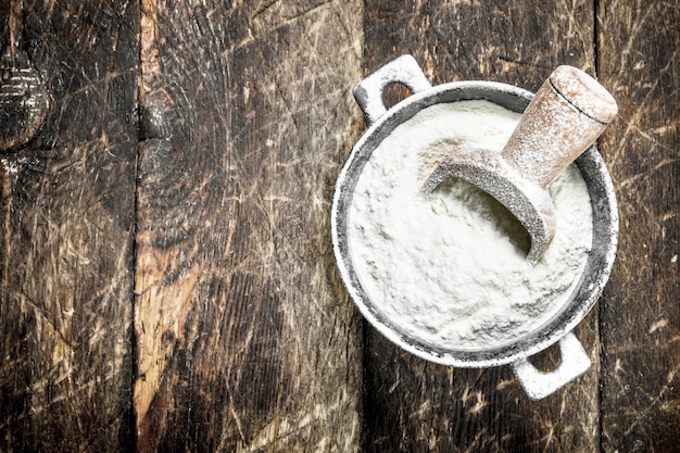 Flour in a bowl. On a wooden background.