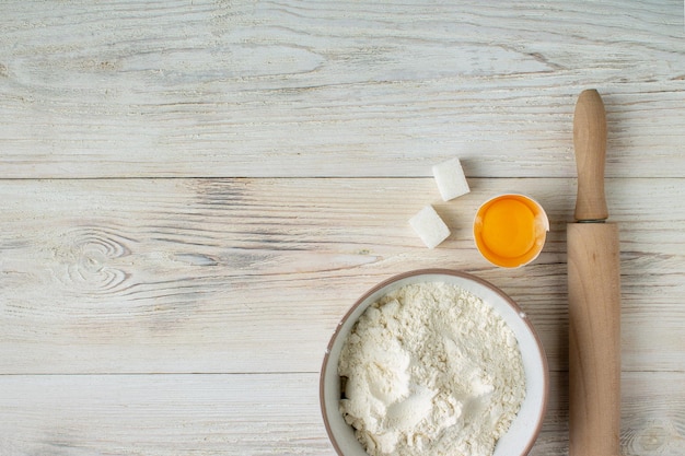 Flour rolling pin egg sugar on a wooden table copy space