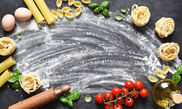 Flour, rolling pin, tomatoes and basil on the table.